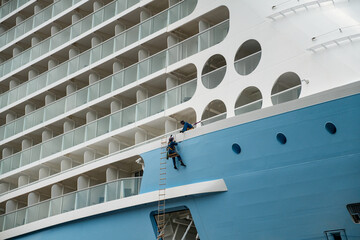Maritime Maintenance: Man Cleaning Blue Cruise Ship in Sydney Harbor