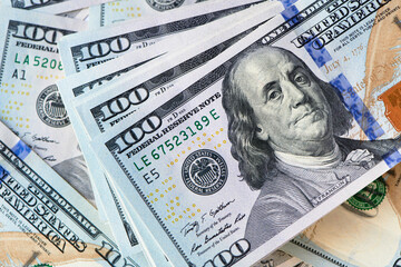 A bundle of one hundred dollar bills against the backdrop of scattered dollars.