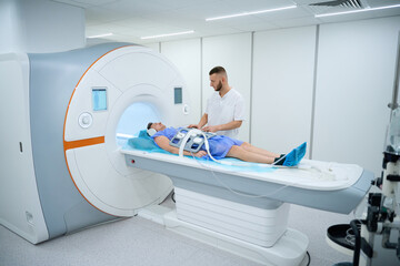Radiographer preparing client for abdominal magnetic resonance imaging procedure
