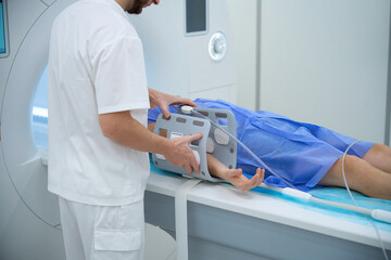 Radiographer preparing client for magnetic resonance imaging of lower arm