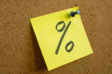 A note with a percent sign as a symbol of profit is pinned to an office board.