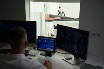Radiologic technologist is performing computed tomography on adult man