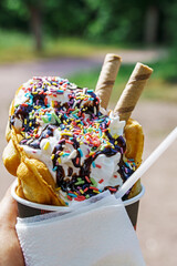 Ice cream with waffles with chocolate topping and colorful sprinkles in hand