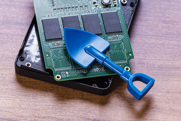 Opened SSD and blue shovel. Cryptocurrency mining concept