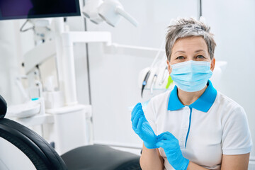 Professional dental therapist wearing protective face mask and sterile gloves