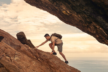 Man hiking climbing up mountain cliff, never give up, people determination,  perseverance, reaching...