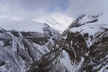 The snow-covered peaks of the mountain range under a sky with clouds, Devil's Valley in the...