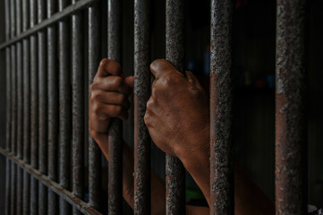 hands of a prisoner behind prison bars