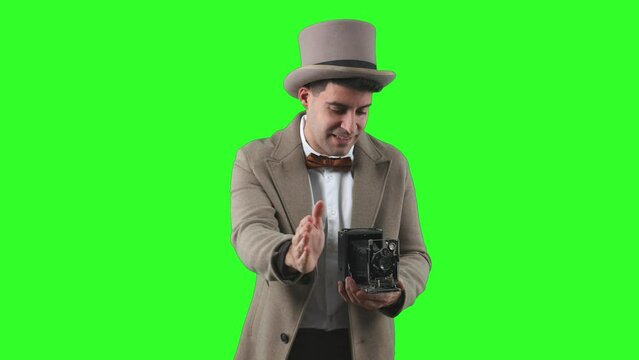 Vintage photographer from the early 20th century, wearing a bowler hat and trench coat, taking a frontal photograph with an antique classic camera chroma green screen