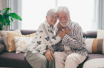 Cheerful handsome senior white haired couple sitting on home sofa laughing have fun together...