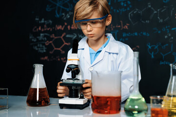 Blonde hair schoolboy in laboratory wear lab coat stand and learn science of chemistry technology...