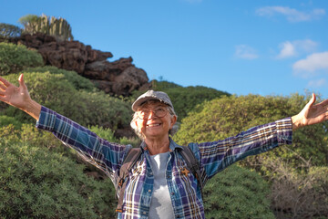 Outdoors activity in nature. Carefree caucasian senior woman with backpack enjoying trekking day in...