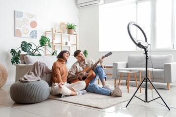 Couple of bloggers with guitar recording video at home