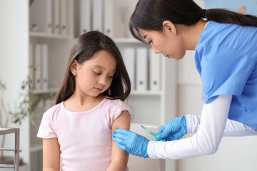 Little Asian girl receiving vaccine in clinic