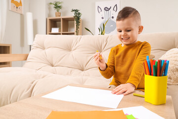 Fototapeta premium Cute little boy drawing with felt-tip pens on table at home
