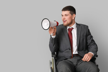 Businessman in wheelchair shouting into megaphone on light background
