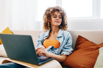 Smiling woman working on laptop in cozy living room, connecting online.