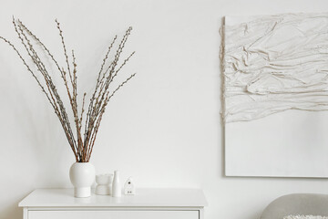 Vase with willow branches on commode in light living room - obrazy, fototapety, plakaty