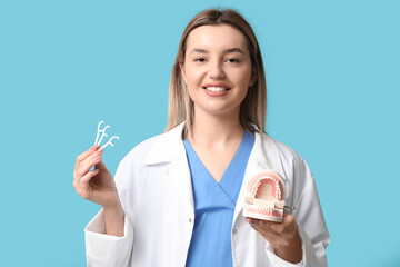 Female dentist with toothpicks and jaw model on blue background