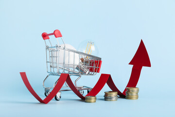 Shopping cart with light bulbs, arrow and coins on blue background. Price rise concept