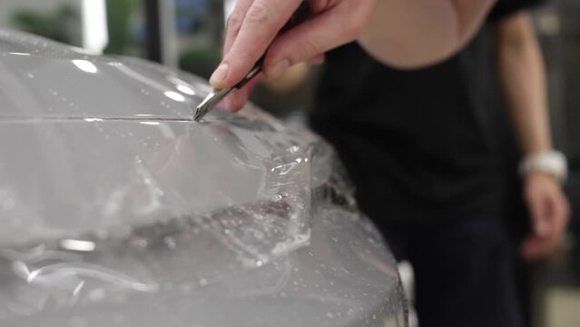 A car wrapping specialist applies a polyurethane film to the car. Selective focus. PPF protective film against chips and scratches. Car wrapping. 