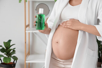Young pregnant woman with mouth rinse in bathroom, closeup