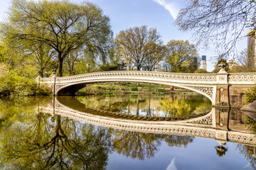 Bow Bridge in Central Park reflecting in water over lake.