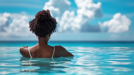 Closeup rear view of an African woman relaxing in the outdoor swimming pool with view to the ocean - Powered by Adobe