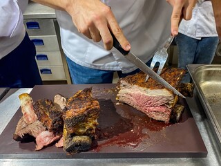 The cook prepares the ribs by cutting them in one piece.