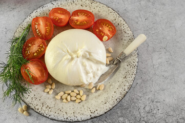 burrata with tomatoes. Caprese salad with tomatoes, burrata cheese and pine nuts. Cutaway soft cheese in a burrata bag. Close-up. Top view, flat lay, - 791132434