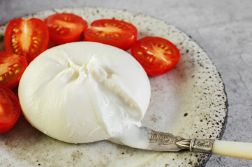 burrata with tomatoes. Caprese salad with tomatoes, burrata cheese and herbs. Soft cheese in a burrata bag. - 791132442