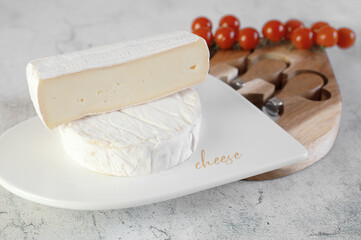 soft cheeses with white mold on a white board. A round small head of brie or camembert cheese. A set of knives and a cheese board on a light background - 791132485