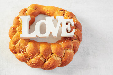 challah, braided bread ring. Round white wheat bread with coarse salt and the inscription Love. The...