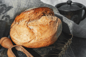 Round white bread. Close-up of white bread with homemade black salt in a wooden scoop on a light...