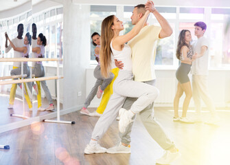 Girl in sport clothes dress dances incendiary tango with male partner during choreography lesson....