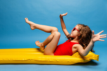 Happy child, red swimsuit, resting on inflatable mattress for swimming, hotel pool. Summer...