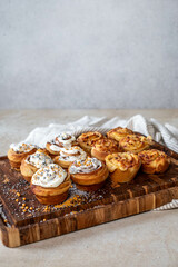 Golden cinnamon rolls with icing on a striped cloth and wood board, ample copy space above for text or design elements, on a white background.