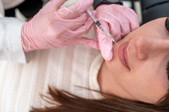 Top view of cosmetologist injecting Botox for lip rejuvenation skincare treatment on a beautiful patient