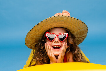 Happy child in straw hat and sunglasses, resting on inflatable mattress for swimming, hotel pool....