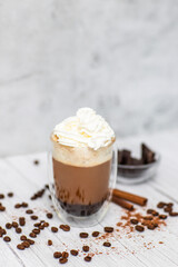 Cocoa drink with black coffee, whipped cream, chocolate on a light wooden table. Tasty coffee drink. 