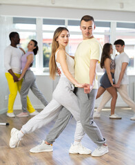 Fototapeta na wymiar Couple of young guy and young woman dancing latin dances in studio