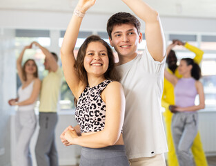 Man and girl are standing next to each other and dancing in pair of salsa. Students practice...