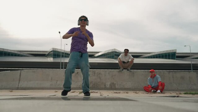 Group of asian break dancer perform street dance with multicultural friend support and moving hip hop music. Attractive handsome hipster practice b boy dance at street. Outdoor sport 2024. Sprightly.