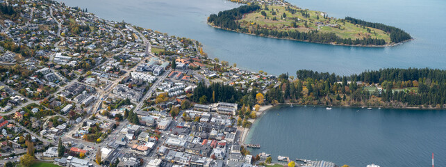 a panoramic aerial view of the town center of Queenstown, with houses and streets by the lake. The resort town of New Zealand is a popular travel destination and sightseeing place to visit.