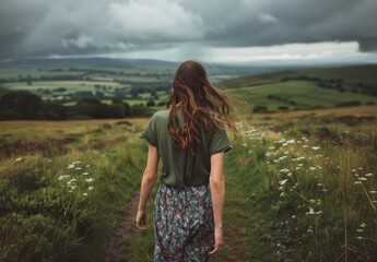 Naklejka premium Woman Walking Down Dirt Road in Field