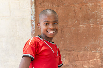 smiling african villager child playing outdoors in front of the house in a village,