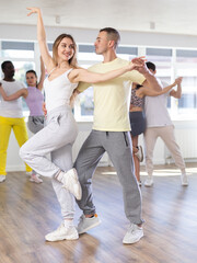 Fototapeta na wymiar Couple male and girl rehearsing pair latino dance in dance studio