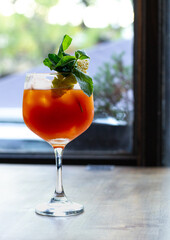 cocktail naranjo en copa a la luz de ventana decorado con menta