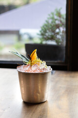 cocktail en vaso de metal y mucho hielo decorado con naranja y piña