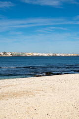 Walking on sea promenade in Corralejo along white popcorn beach with white corals, black rocks, blue water, Fuerteventura, Canary islands, Spain
